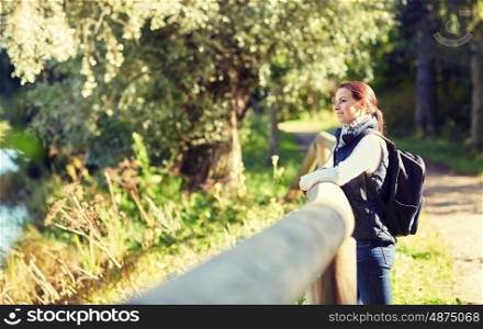 travel, tourism, hike and people concept - happy woman with backpack outdoors