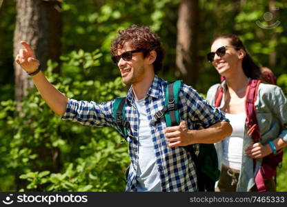 travel, tourism, hike and people concept - mixed race couple with backpacks in forest. mixed race couple with backpacks hiking in forest