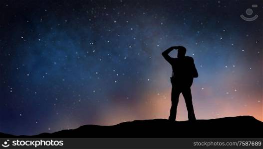 travel, tourism, hike and people concept - silhouette of traveler standing on edge and looking far away over starry night sky or space background. traveler standing on edge and looking far away