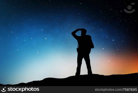 travel, tourism, hike and people concept - silhouette of traveler standing on edge and looking far away over starry night sky or space background. traveler standing on edge and looking far away