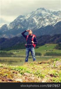 travel, tourism, hike and people concept - tourist with beard, backpack standing on edge of hill and looking far away over mountains background