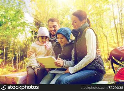 travel, tourism, hike and technology concept - happy family with tablet pc computer and backpacks at camp in woods. happy family with tablet pc and backpacks at camp