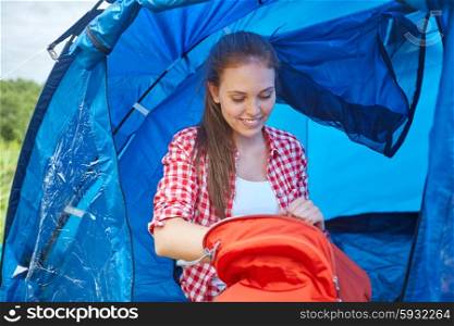 travel, tourism, hike, camping and people concept - happy young woman with backpack sitting in tent