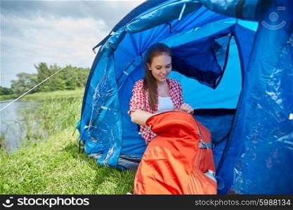travel, tourism, hike, camping and people concept - happy young woman with backpack sitting in tent