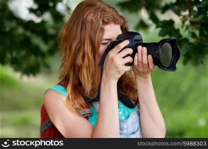 travel, tourism, hike, hobby and people concept - young woman with backpack and camera photographing outdoors