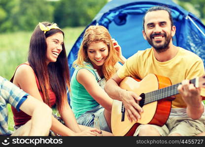 travel, tourism, hike, picnic and people concept - group of happy friends with tent and drinks playing guitar at camping