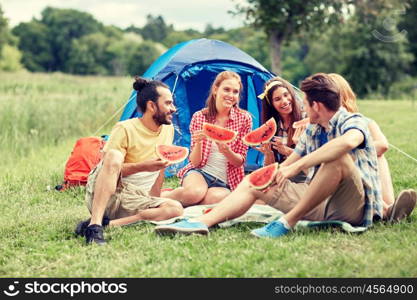 travel, tourism, hike, picnic and people concept - group of happy friends with tent eating watermelon at camping