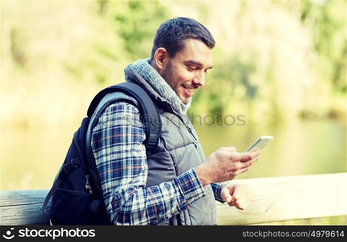 travel, tourism, hike, technology and people concept - happy man with backpack and smartphone outdoors. happy man with backpack and smartphone outdoors