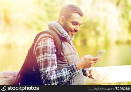 travel, tourism, hike, technology and people concept - happy man with backpack and smartphone outdoors. happy man with backpack and smartphone outdoors