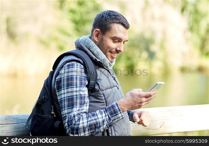 travel, tourism, hike, technology and people concept - happy man with backpack and smartphone outdoors