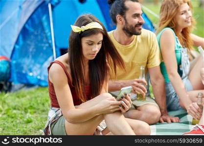 travel, tourism, hike, technology and people concept - happy young woman with smartphone and friends at camping