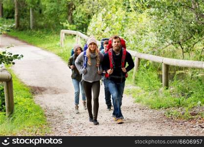 travel, tourism, hiking and people concept - group of happy friends or travelers with backpacks. happy friends or travelers hiking with backpacks