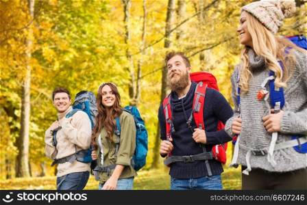 travel, tourism, hiking and people concept - group of smiling friends or travelers with backpacks in autumn forest. hiking friends or travelers with backpacks