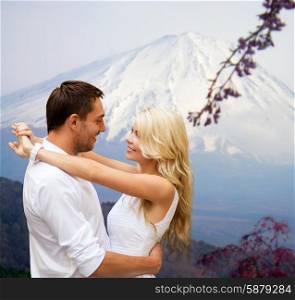 travel, tourism, honeymoon, people and love concept - happy couple hugging over japan mountains background