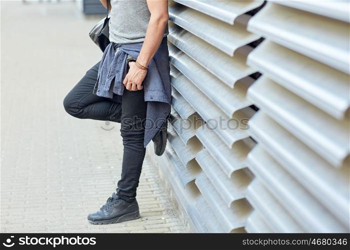travel, tourism, lifestyle and people concept - close up of man with backpack standing at city street wall