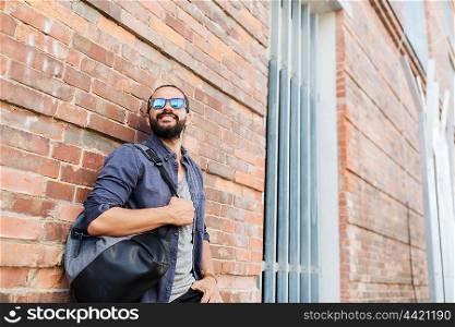 travel, tourism, lifestyle and people concept - happy smiling man with backpack standing at city street wall