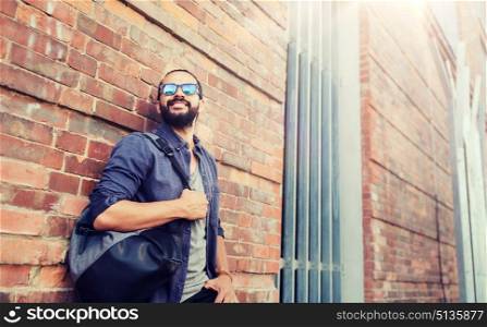 travel, tourism, lifestyle and people concept - happy smiling man with backpack standing at city street wall. happy man with backpack standing at city street. happy man with backpack standing at city street