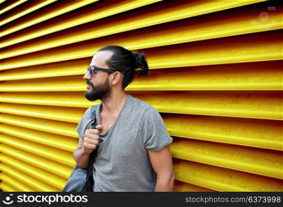travel, tourism, lifestyle and people concept - man in sunglasses with bag standing at city street over ribbed yellow wall background. man in sunglasses with bag standing at street wall