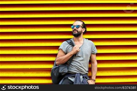 travel, tourism, lifestyle and people concept - man in sunglasses with bag standing at city street over ribbed yellow wall background. man in sunglasses with bag standing at street wall