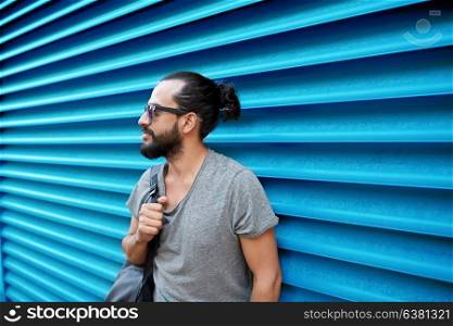 travel, tourism, lifestyle and people concept - man in sunglasses with bag standing at city street over ribbed blue wall background. man in sunglasses with bag standing at street wall