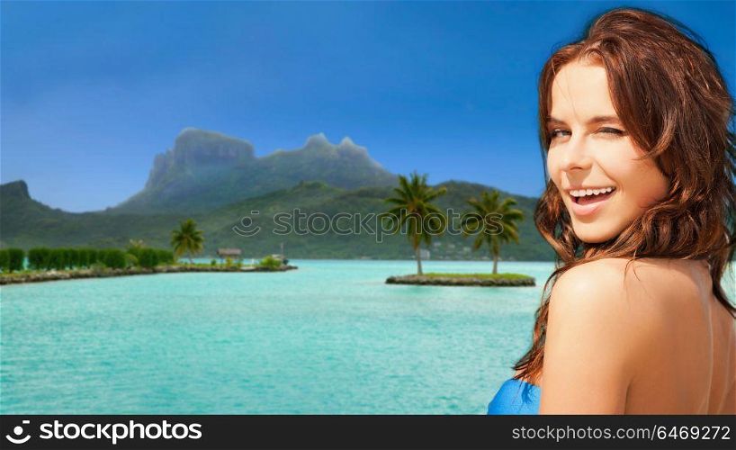 travel, tourism, summer holidays and vacation concept - happy young woman posing in bikini swimsuit at touristic resort over bora bora island beach background. happy woman in bikini swimsuit on bora bora beach