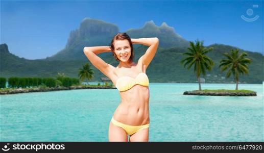 travel, tourism, summer holidays and vacation concept - happy young woman posing in bikini swimsuit at touristic resort over bora bora island beach background. happy woman in bikini swimsuit on bora bora beach. happy woman in bikini swimsuit on bora bora beach