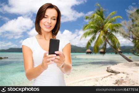 travel, tourism, summer holidays and vacation concept - happy young woman taking selfie by smartphone over exotic tropical beach with palm tree and bungalow sheds background. woman taking selfie by smartphone on beach. woman taking selfie by smartphone on beach