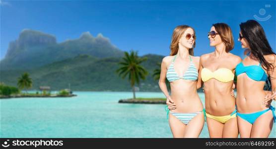 travel, tourism, summer holidays and vacation concept - smiling young women in bikini at touristic resort over exotic bora bora island beach background. smiling young women in bikini on bora bora beach