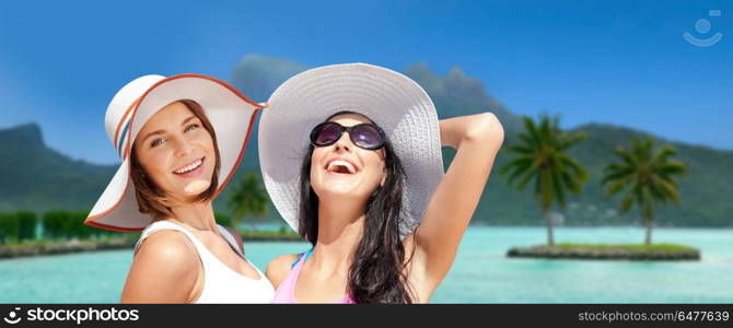 travel, tourism, summer holidays and vacation concept - smiling young women in hats at touristic resort over exotic bora bora island beach background. smiling young women in hats on bora bora beach. smiling young women in hats on bora bora beach