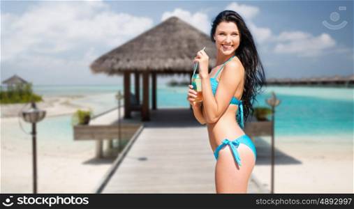 travel, tourism, summer holidays, vacation and people concept - happy beautiful woman with bottle of drink and straw over exotic tropical beach with bungalow shed background