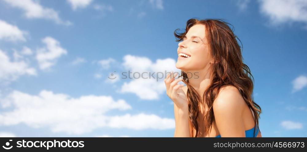 travel, tourism, summer vacation and people concept - happy beautiful woman over blue sky and clouds background