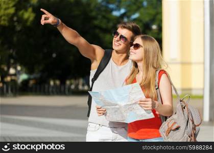 travel, tourism, summer vacation and people concept - smiling couple with map and backpack pointing finger in city
