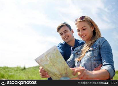travel, tourism, summer vacation, location and people concept - happy couple with map outdoors