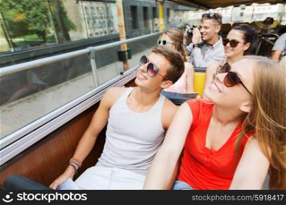 travel, tourism, summer vacation, sightseeing and people concept - group of smiling teenage friends in sunglasses traveling by tour bus