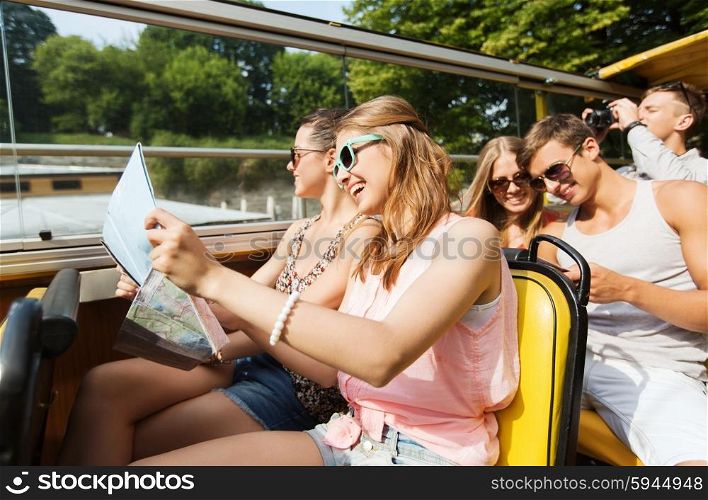 travel, tourism, summer vacation, sightseeing and people concept - group of smiling teenage friends in sunglasses with map traveling by tour bus