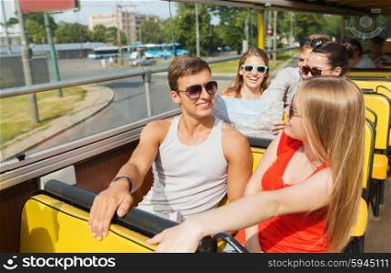 travel, tourism, summer vacation, sightseeing and people concept - group of smiling teenage friends in sunglasses with map traveling by tour bus
