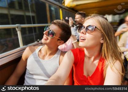 travel, tourism, summer vacation, sightseeing and people concept - happy teenage couple in sunglasses traveling by tour bus