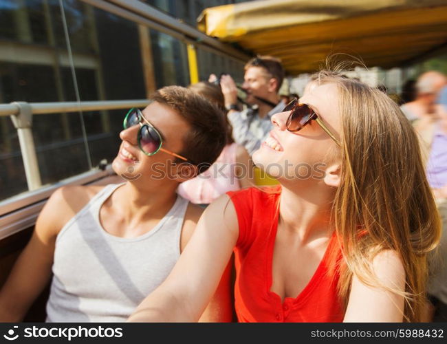 travel, tourism, summer vacation, sightseeing and people concept - happy teenage couple in sunglasses traveling by tour bus