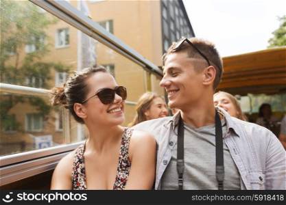 travel, tourism, summer vacation, sightseeing and people concept - smiling teenage couple in sunglasses traveling by tour bus