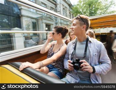travel, tourism, summer vacation, sightseeing and people concept - smiling teenage couple with camera traveling by tour bus