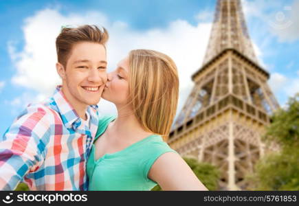 travel, tourism, summer vacation, technology and love concept - happy couple taking selfie with smartphone or camera and kissing over eiffel tower and sky background