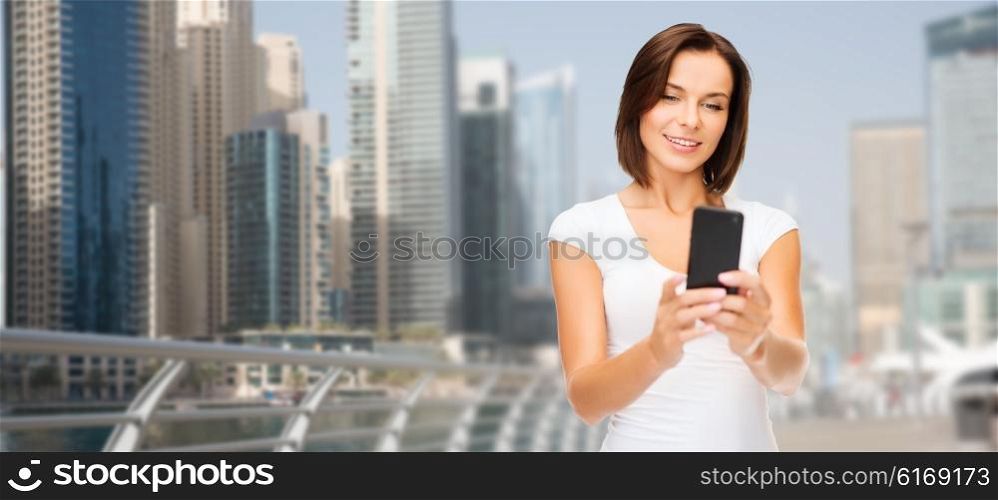 travel, tourism, summer vacation, technology and people - happy young woman taking selfie picture by smartphone over dubai city waterfront background
