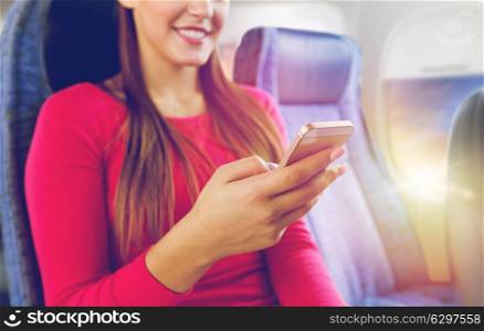 travel, tourism, technology and air flights concept - close up of happy young woman sitting in plane with smartphone over porthole background. close up of woman sitting in plane with smartphone. close up of woman sitting in plane with smartphone