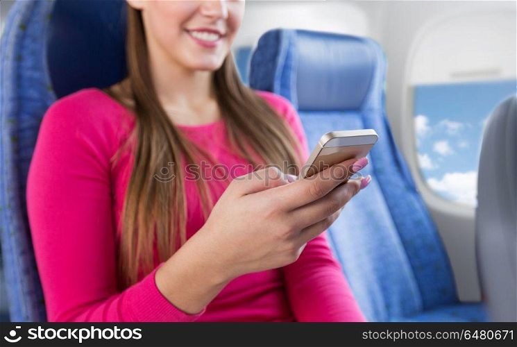 travel, tourism, technology and air flights concept - close up of happy young woman sitting in plane with smartphone over porthole background. close up of woman sitting in plane with smartphone. close up of woman sitting in plane with smartphone
