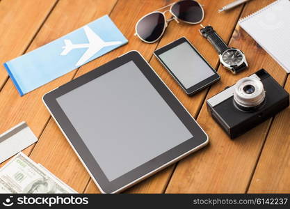 travel, tourism, technology and objects concept - close up of smartphone with tablet pc computer, airplane ticket and personal stuff