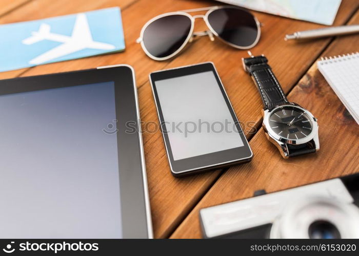 travel, tourism, technology and objects concept - close up of smartphone with tablet pc computer, airplane ticket and personal stuff