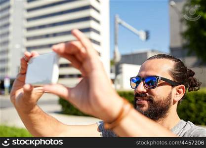 travel, tourism, technology and people concept - smiling man taking video or selfie by smartphone on summer city street