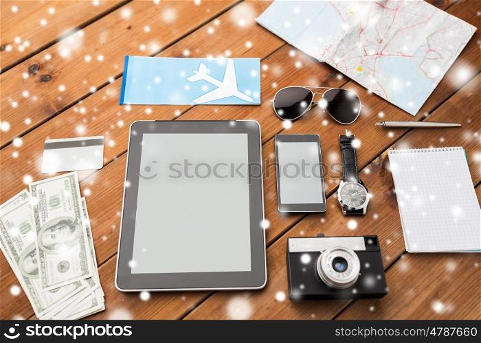 travel, tourism, technology and winter holidays concept - smartphone with tablet pc computer, airplane ticket and personal stuff over snow