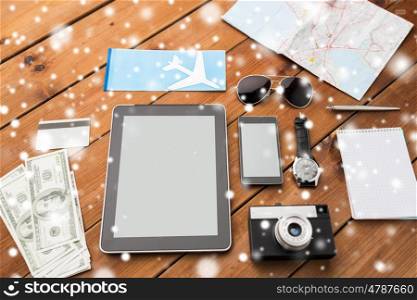 travel, tourism, technology and winter holidays concept - smartphone with tablet pc computer, airplane ticket and personal stuff over snow