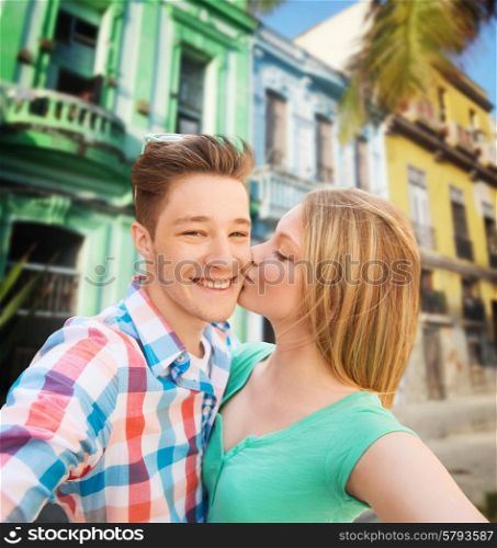 travel, tourism, technology, love and people concept - smiling couple kissing and taking selfie over latin american city street background